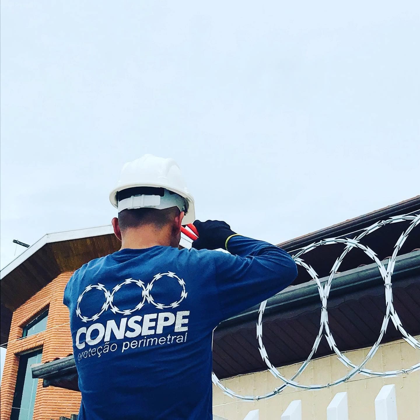 Técnico da Consepe instalando concertina em muro residencial